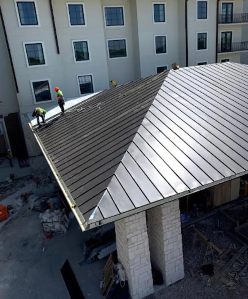 Crew installing standing seam metal roof panels on a commercial project in Spring Valley Lake